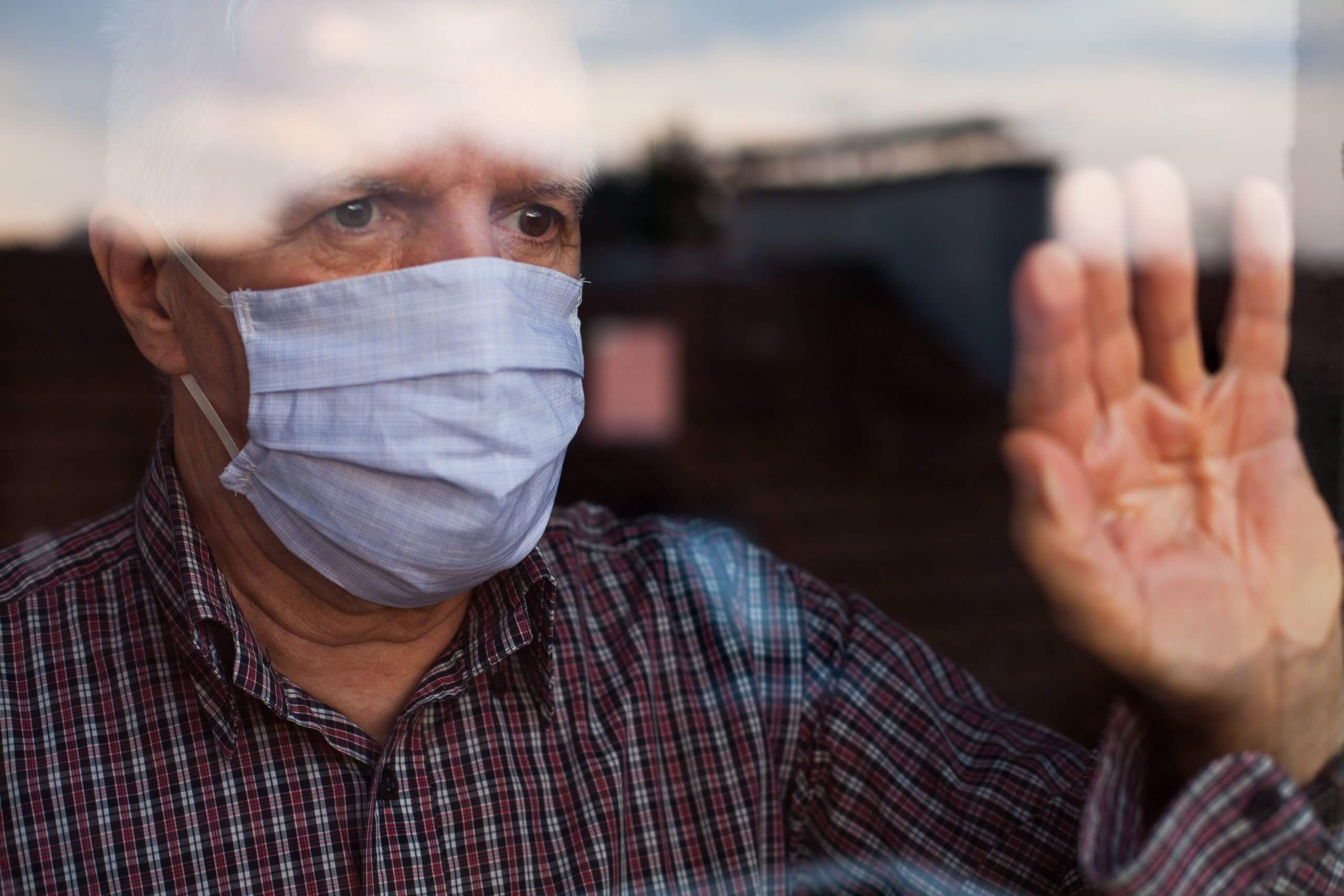 man looking out the window of a nursing home