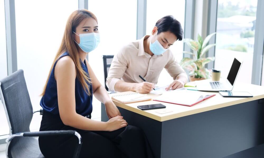 Woman and Man wearing masks during a meeting.