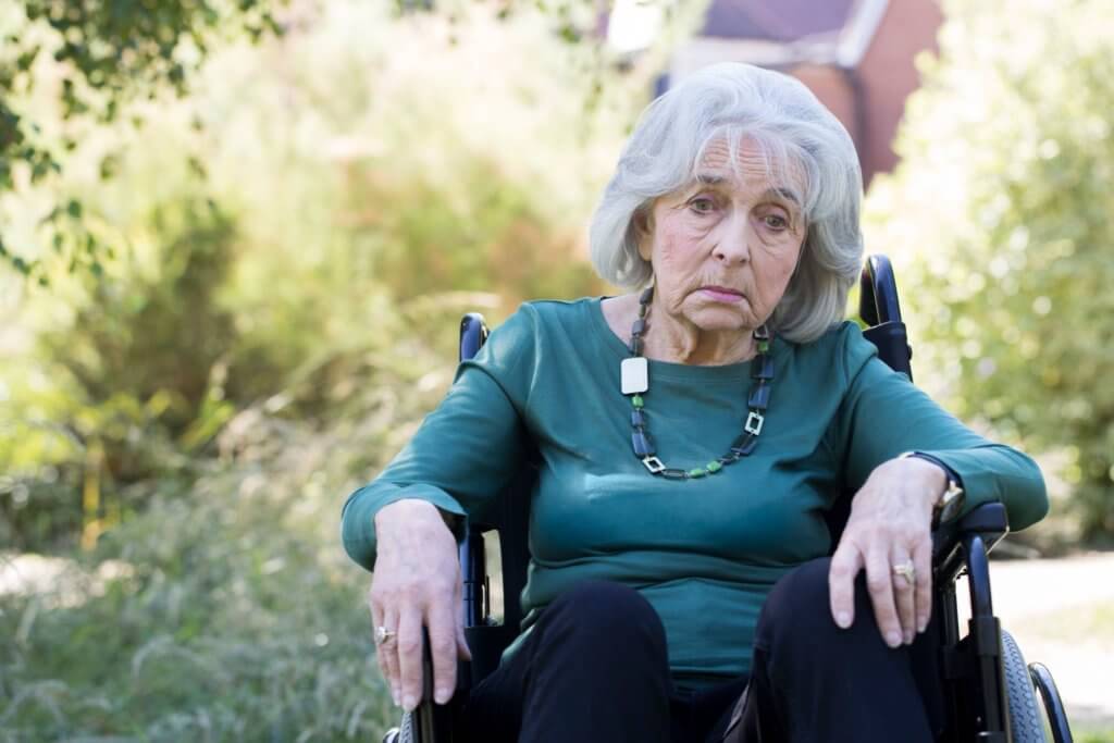 older woman sitting in nursing home chair during COVID lockdown