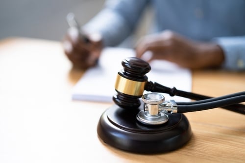 Gavel, stethoscope, and medical malpractice text on courtroom background